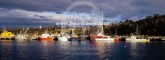 Yachts and fishing boats moored at a jetty on a sunny afternoon. Eden, New South Wales, Australia.