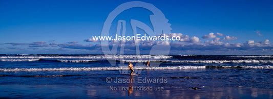 Teenage boys play in the rolling surf at sunset on a summer afternoon. Jan Juc, Victoria, Australia.