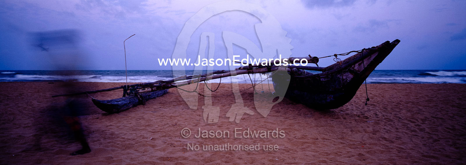 A fishing boat hauled onto a tropical island beach before dawn. Negombo Beach, Sri Lanka.