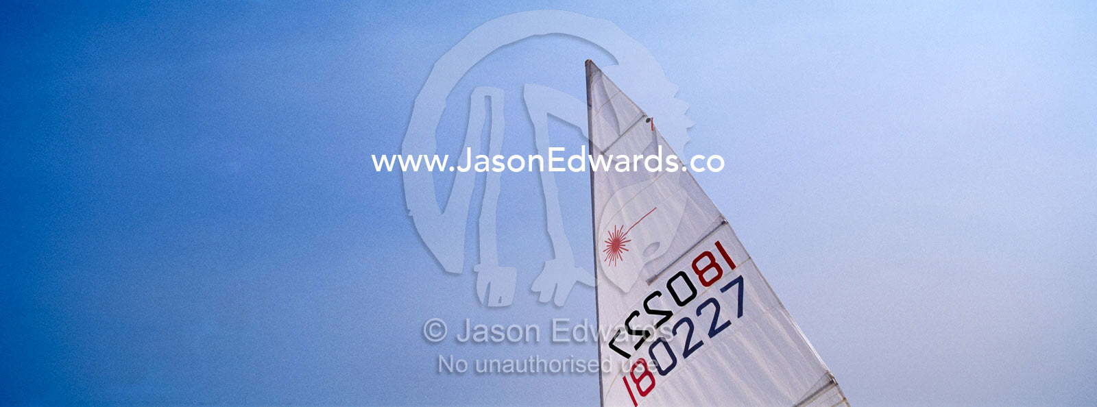 A small yacht sail knifes through a clear blue summer sky. Port Melbourne, Victoria, Australia.