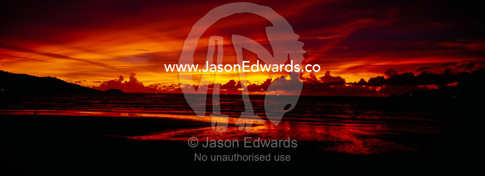 A flaming sunset erupts over Patong's famous beach and promenade. Patong Beach, Phuket, Thailand.