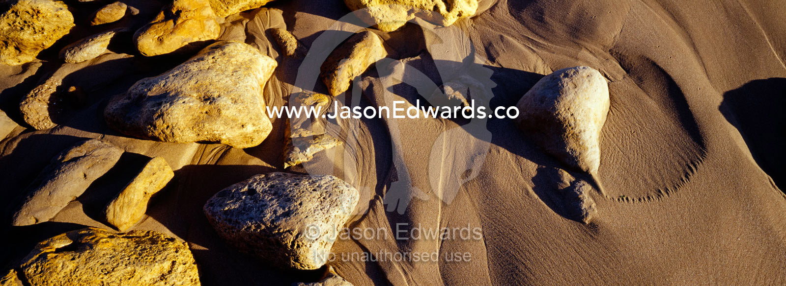 Waves leave beautiful patterns trailing behind boulders on the beach. Jan Juc, Victoria, Australia.