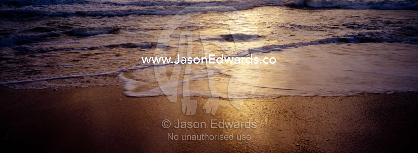 Warm waves roll onto a deserted tropical island beach at sunset. Negombo Beach, Sri Lanka.
