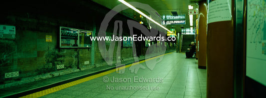 A lone commuter reads a novel on an empty railway platform before dawn Shimbashi Station, Tokyo, Japan.