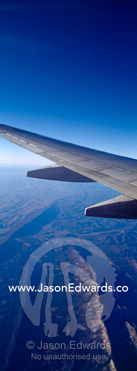 A passenger aircraft wing in flight over a rugged mountain range. Central United States of America, USA.