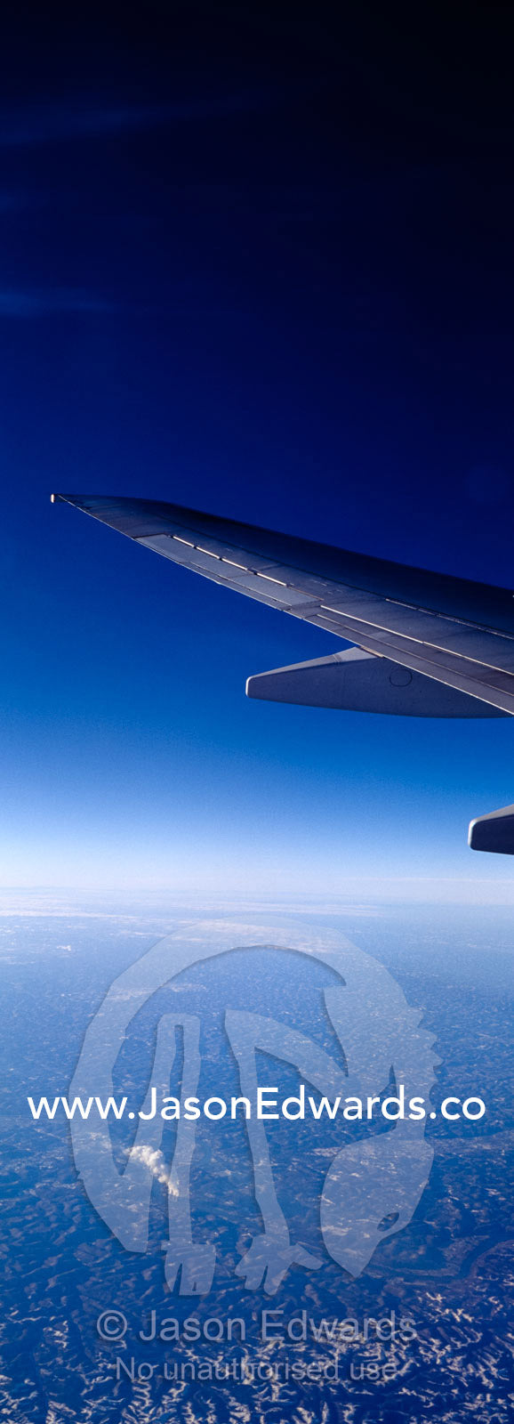 A passenger aircraft wing in flight over a distant power station. United States of America.