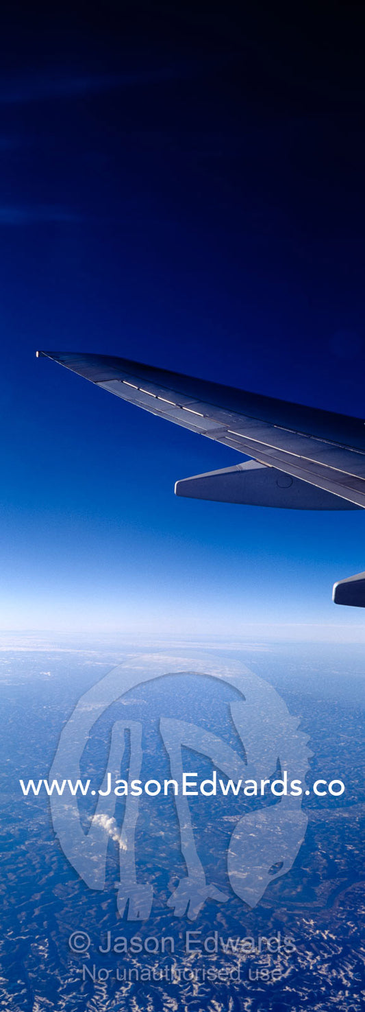 A passenger aircraft wing in flight over a distant power station. United States of America.