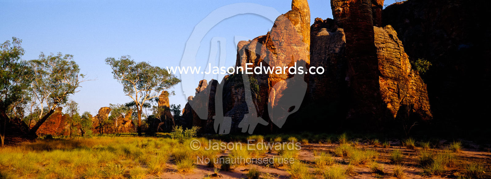 Ancient red rock formations rise above spinifex grasslands at sunset. Limmen National Park, Northern Territory, Australia.