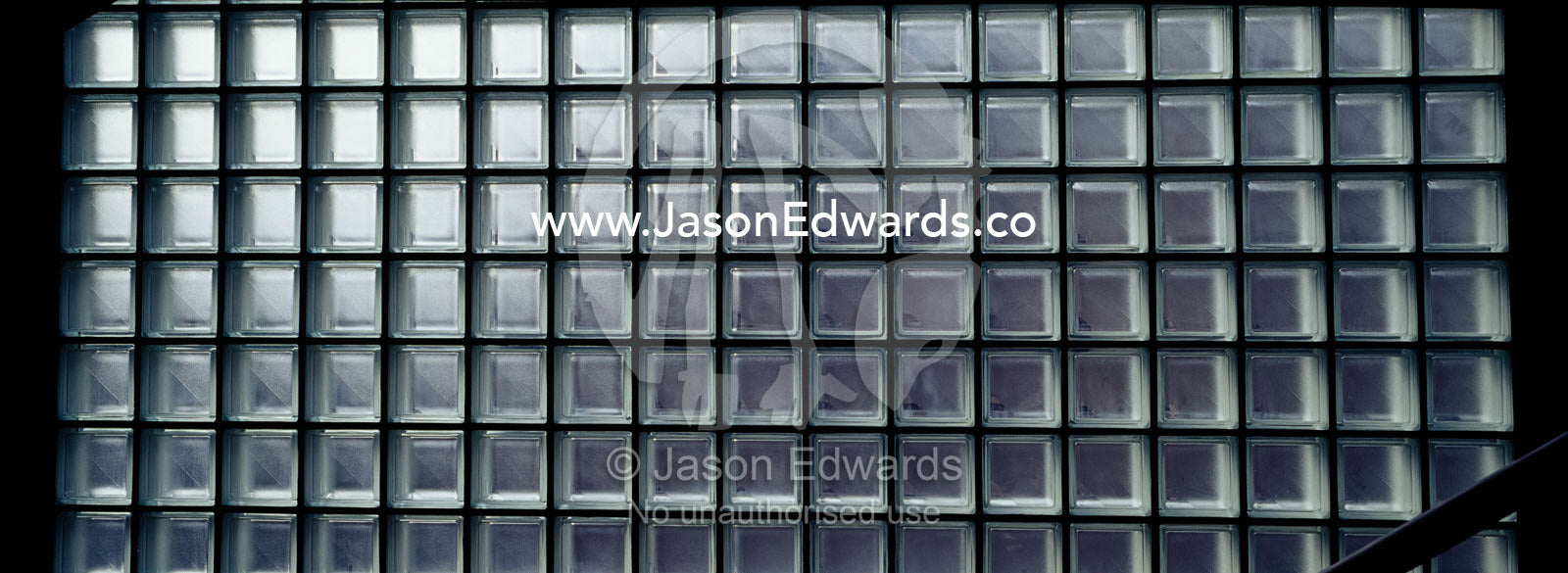 Daylight seeps through a glass brick wall in a museum stairwell. Tokyo Metropolitan Museum of Photography, Japan.