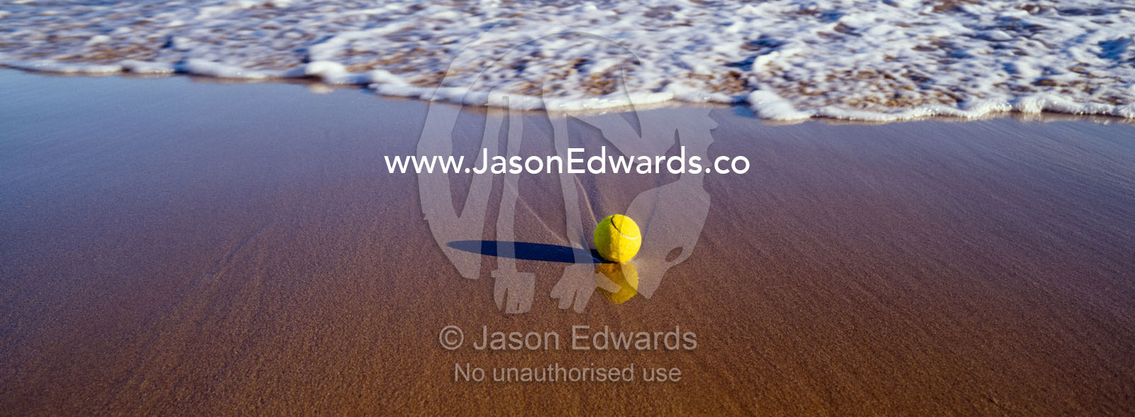 A lone tennis ball on a beach awaits waves to carry it out to sea. Jan Juc, Victoria, Australia.