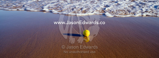 A lone tennis ball on a beach awaits waves to carry it out to sea. Jan Juc, Victoria, Australia.
