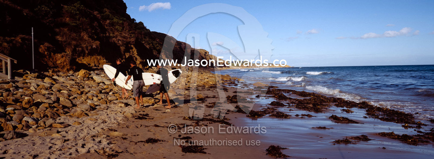 Teenage boys return to the beach from surfing on a summer afternoon. Jan Juc, Victoria, Australia.