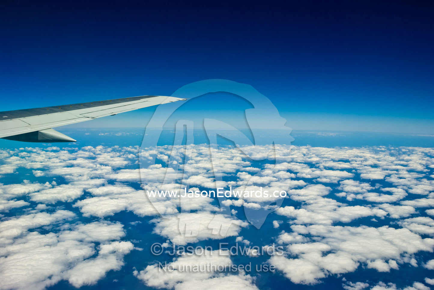 A jet wings it's way over a cloud bank along the Queensland coast. North Queensland, Australia.