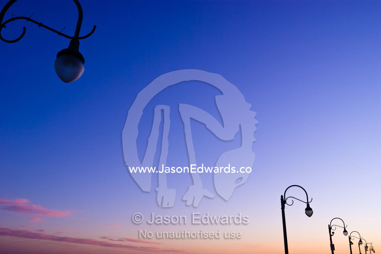 Antique lights hang over the boardwalk of Santa Monica pier at sunset. Santa Monica, Los Angeles, California, United States of America.