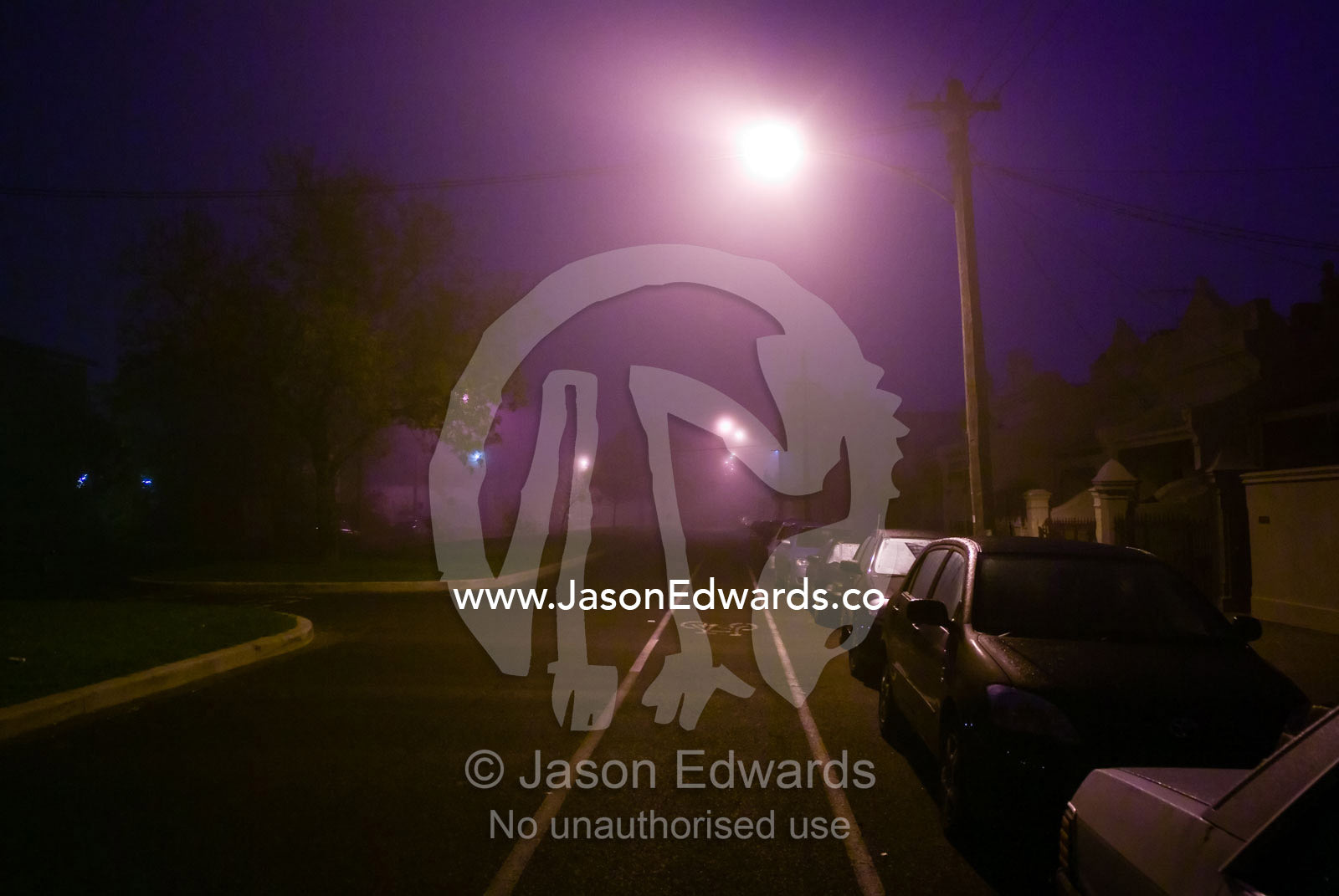 Artificial lights illuminate a suburban street on a foggy night. North Carlton, Victoria, Australia.