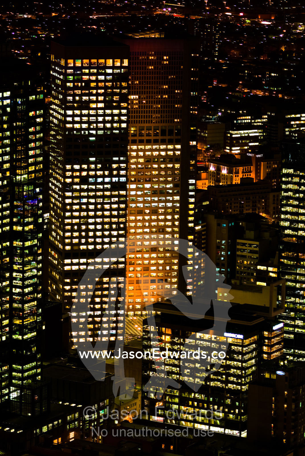 Energy hungry office towers illuminate the night sky in a major city. Melbourne, Victoria, Australia.