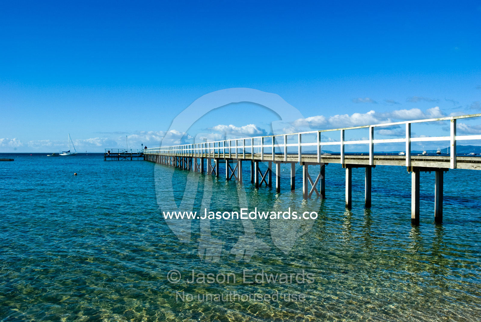 A small wooden jetty reaches into a bay on a clear winters day. Sorrento, Victoria, Australia.