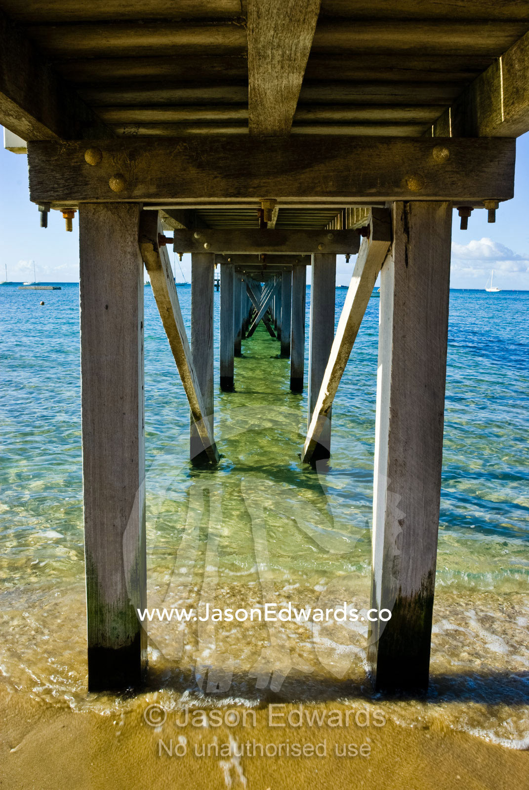 A small wooden jetty reaches into a bay on a clear winters day. Sorrento, Victoria, Australia.