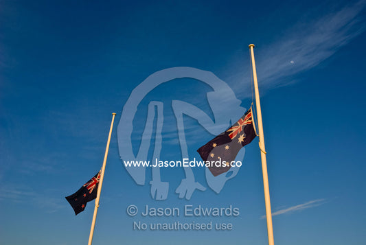 Dawn on ANZAC Day and Australian and New Zealand flags at half mast. Point Danger, Torquay, Victoria, Australia.