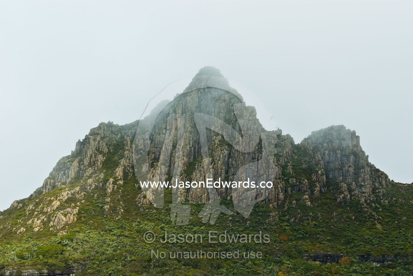 Clouds and mist shroud the jagged granite peaks of Cradle Mountain. Cradle Mountain Lake St Clair National Park, Tasmania, Australia.