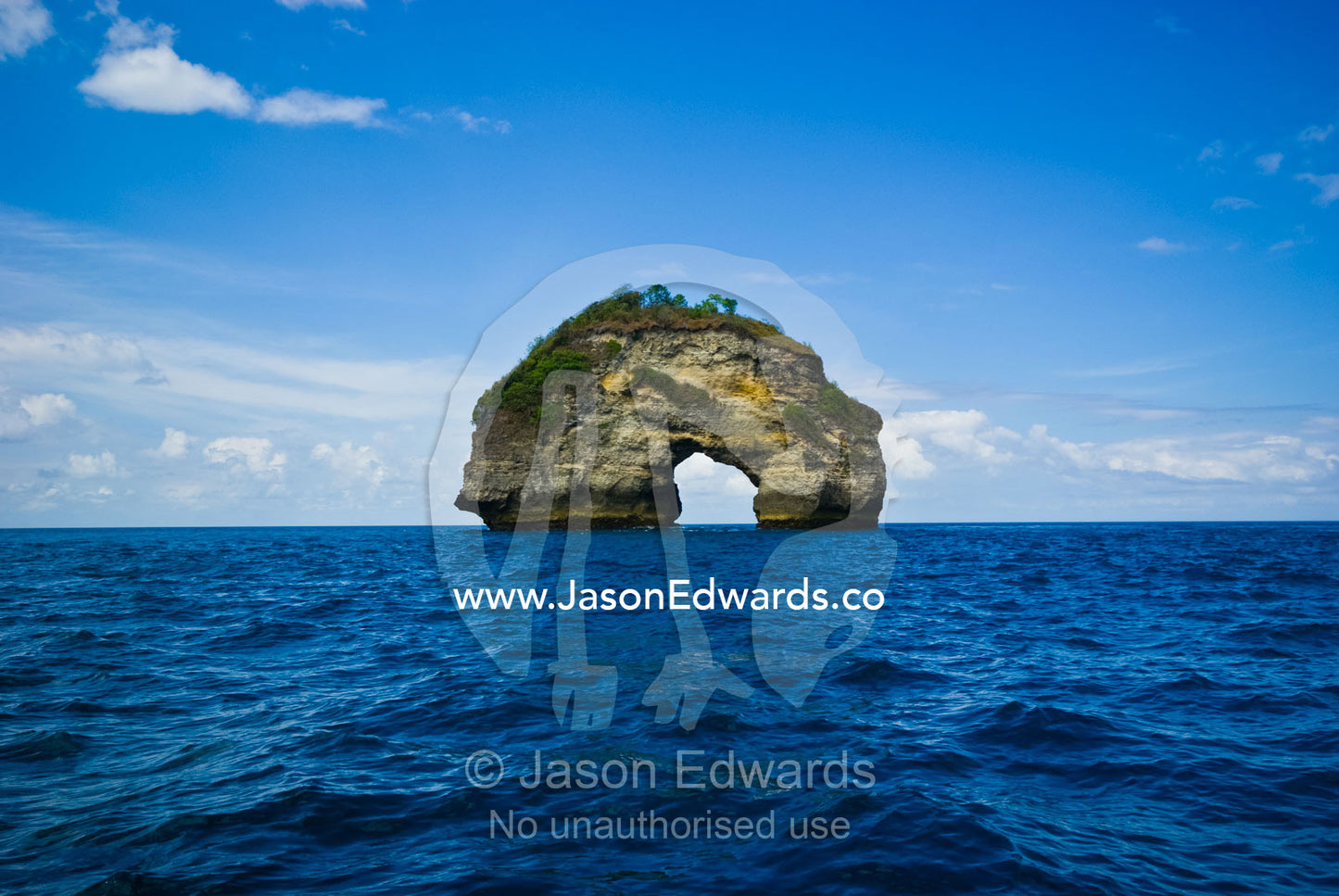 A hole eroded through a limestone pillar by the ocean near Manta Point Nusa Penida Island, Bali, Indonesia.
