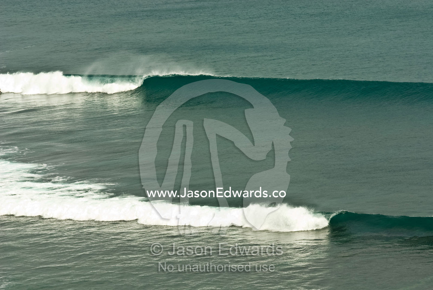 Lines of clean tropical swell peel in over a reef in Bali. Bukit Peninsula, Bali, Indonesia.