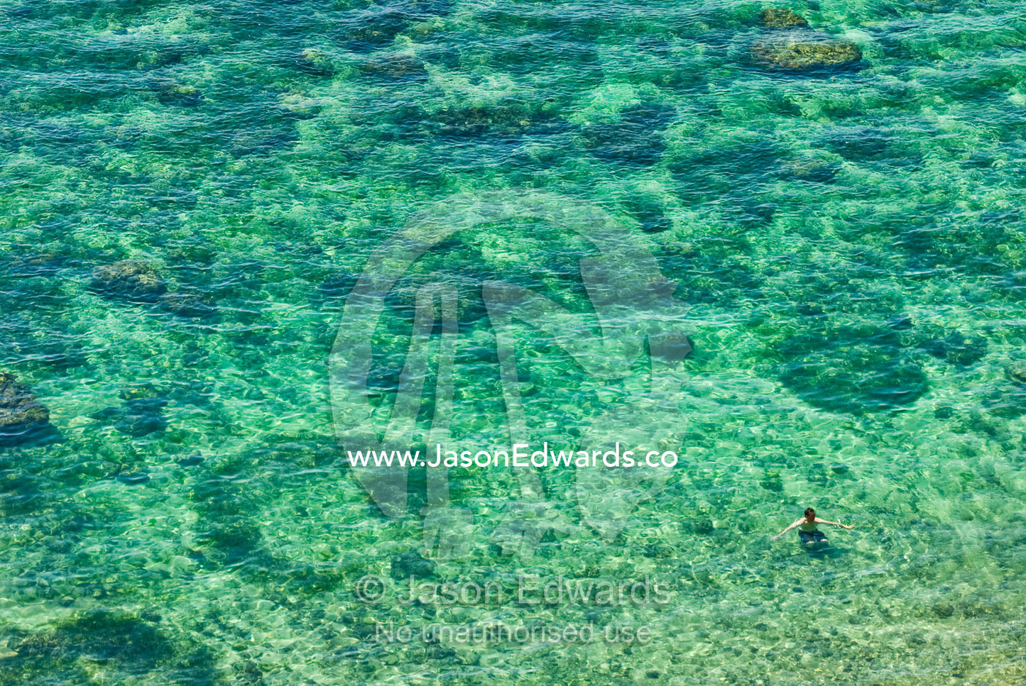 A swimmer relaxes in a sheltered bay on the inside of a tropical reef Bingin, Bukit Peninsula, Bali, Indonesia.