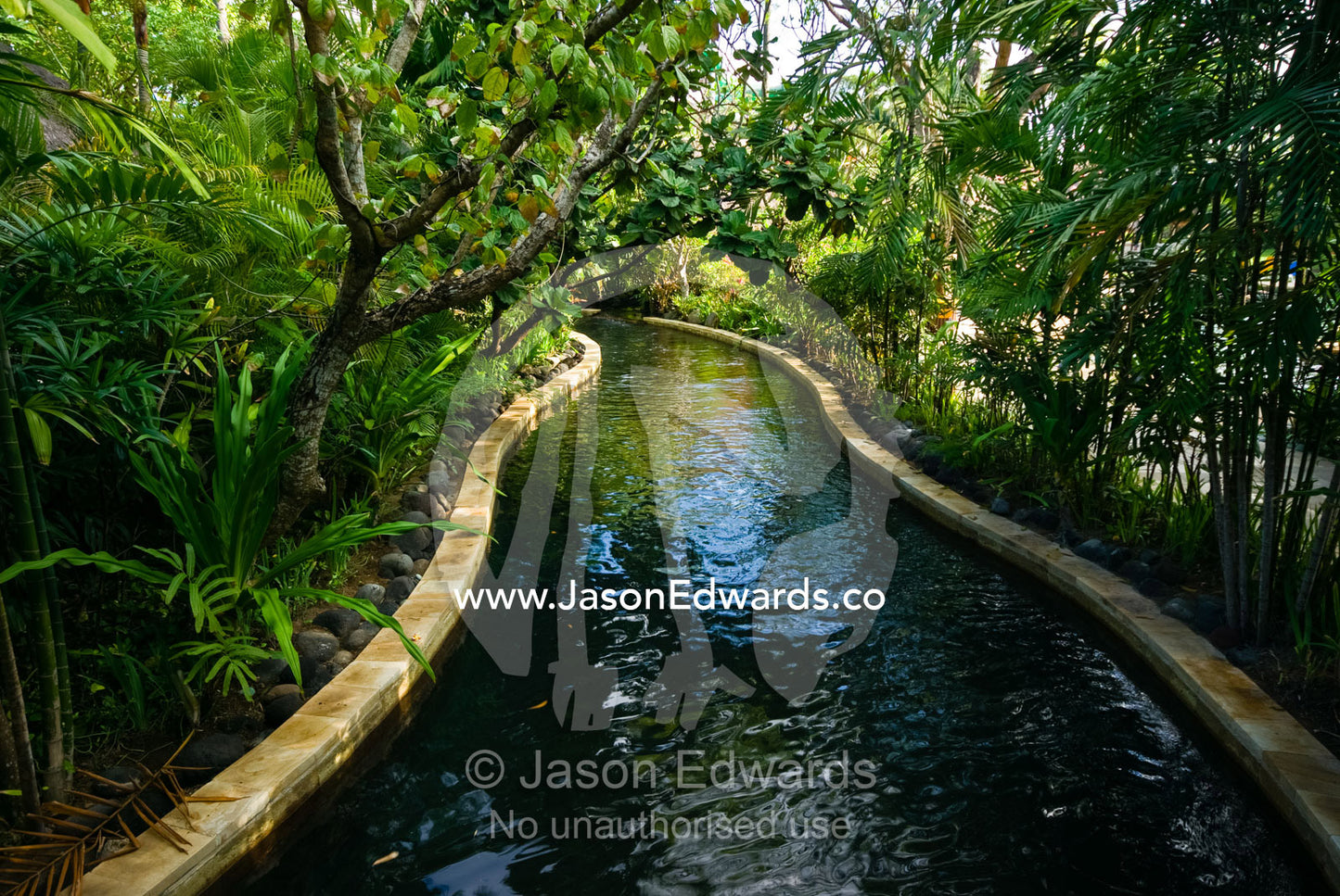 An artificial waterway lined with tropical plants in a water park. Waterbom Park, Tuban, Bali, Indonesia.