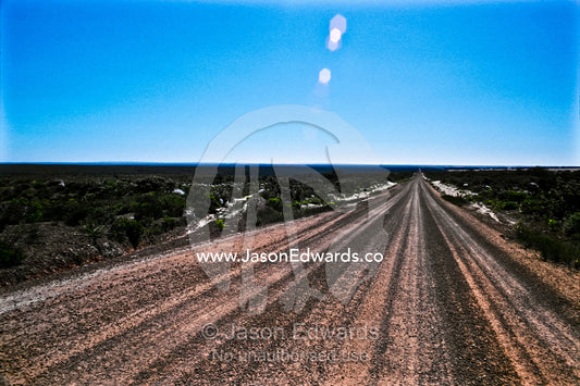 A long, straight dirt road through the desert under a blistering sun. Nambung National Park, Western Australia, Australia.