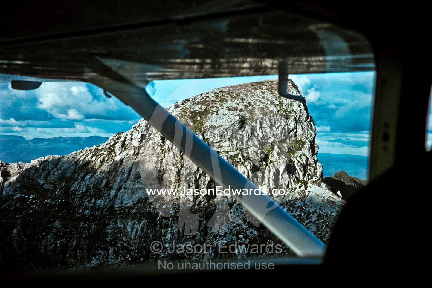 A light plane flies by Frenchman's Cap a striking quartzite mountain. SouthWest National Park, Tasmania, Australia.