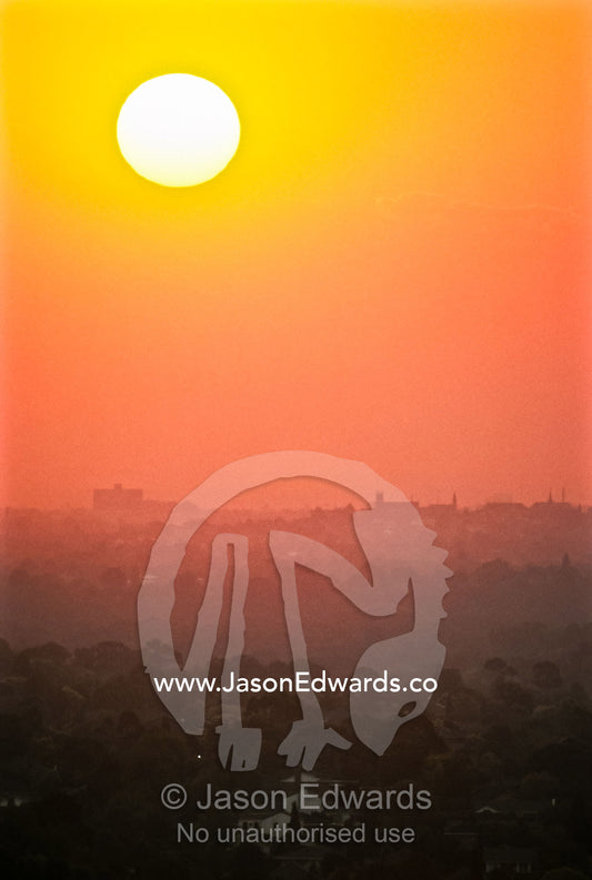 Sunset pierces a haze of pollution settled over a cities urban sprawl. Suburbs of Melbourne, Victoria, Australia.