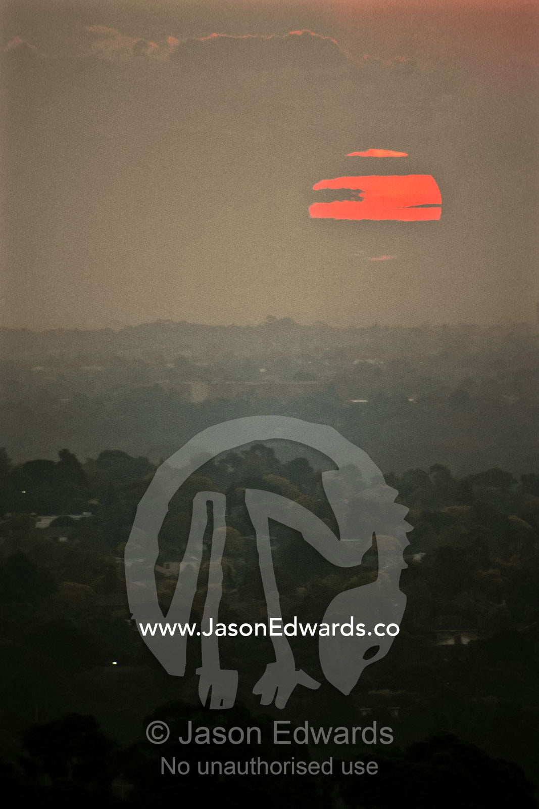 Sunset pierces a haze of pollution settled over a cities urban sprawl. Suburbs of Melbourne, Victoria, Australia.
