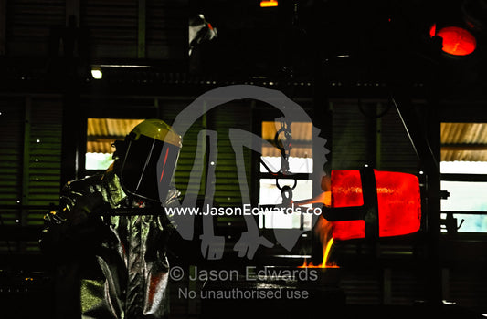 Insulated from the heat a mine worker pours molten gold into a mould. Hannan���s North Tourist Mine, Kalgoorlie-Boulder, Western Australia, Australia.
