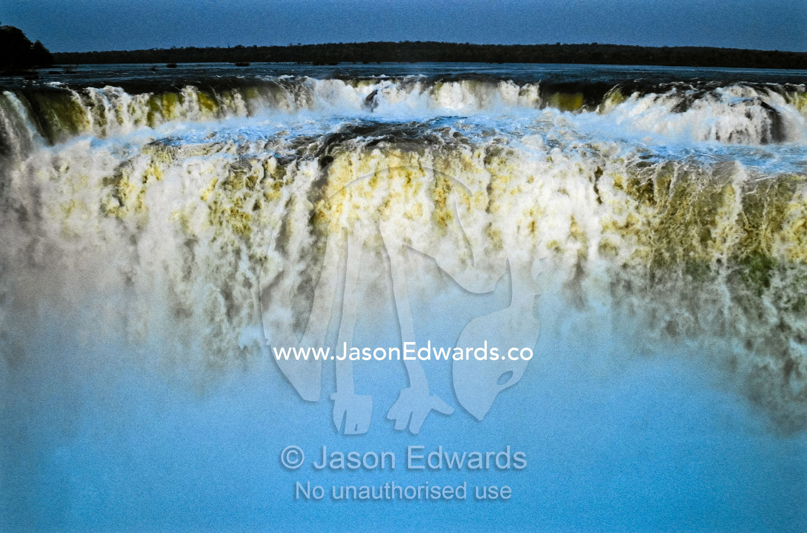 Mist rises from crushing pillars of water cascading over a precipice. Iguazo Falls, Iguazu National Park, Argentina.