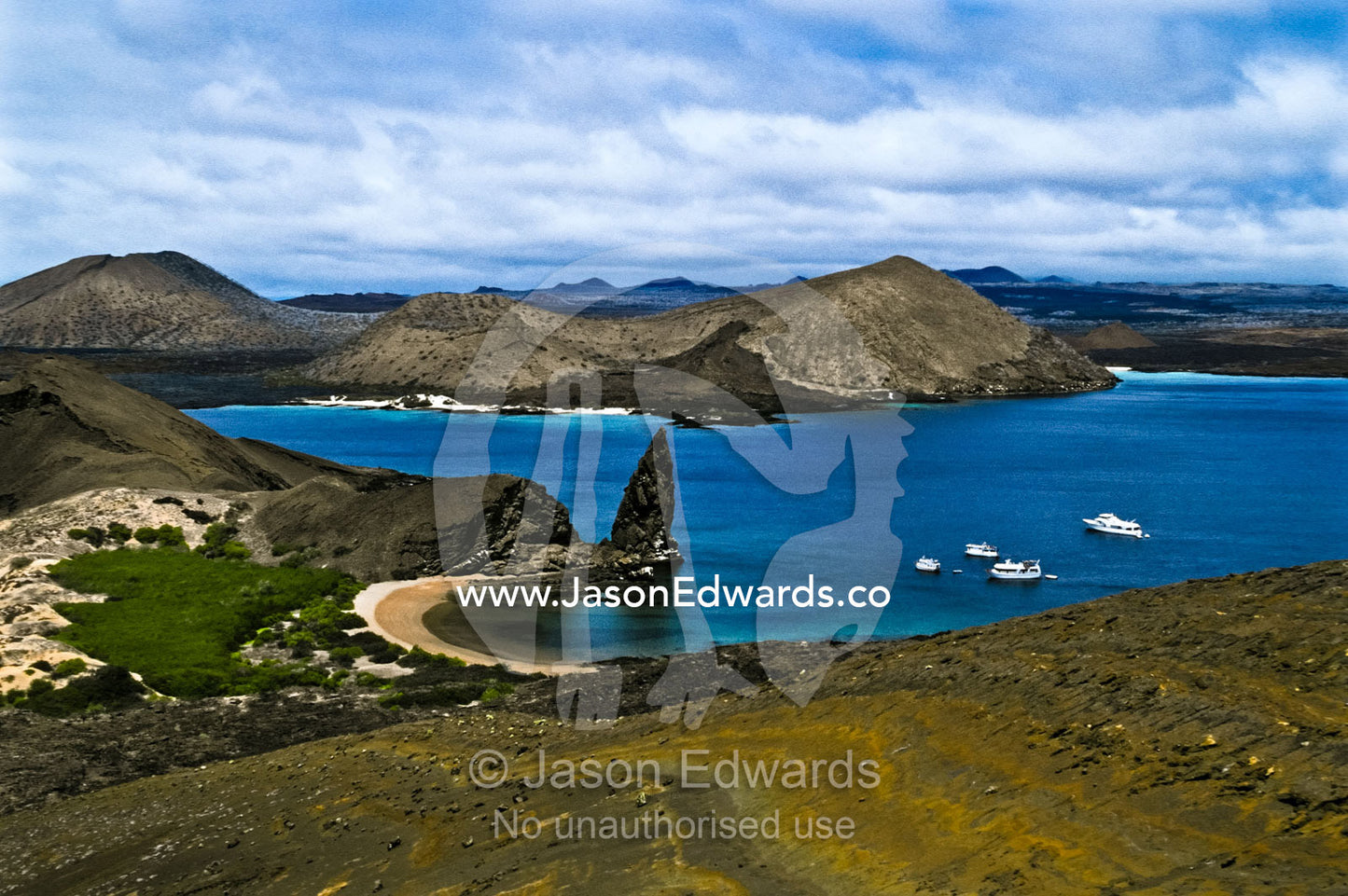 Ancient lava flows and extinct volcano cones rise from turquoise seas. Pinnacle Rock, Bartolome Island, Galapagos Islands, Ecuador.