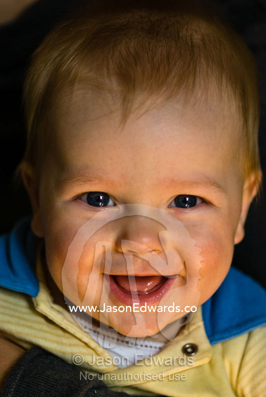 A beaming baby boy shows his toothless smile and bright shiny eyes. Collingwood, Victoria, Australia.