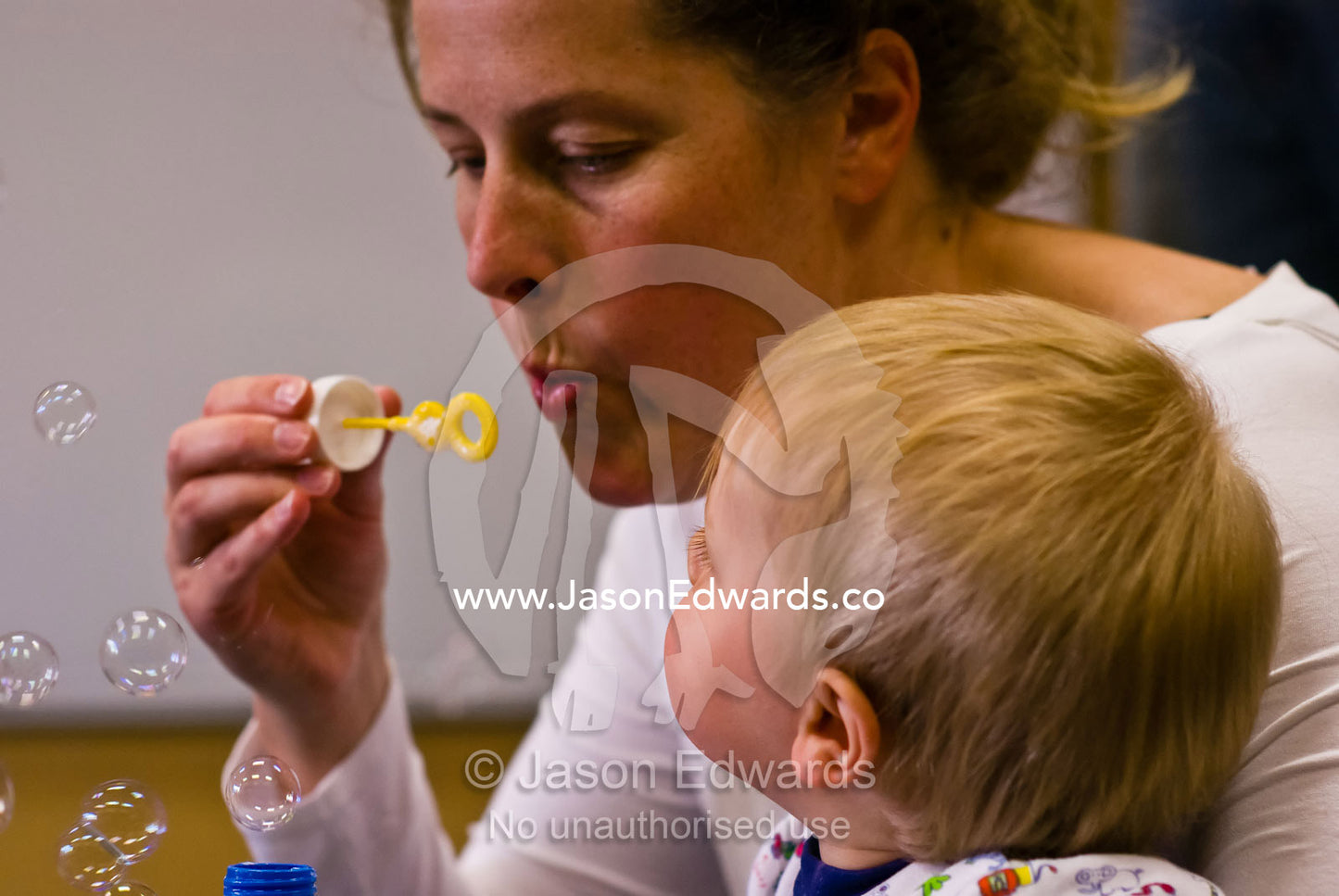 A mother and her fascinated baby boy play a game of blowing bubbles. Carlton North, Victoria, Australia.