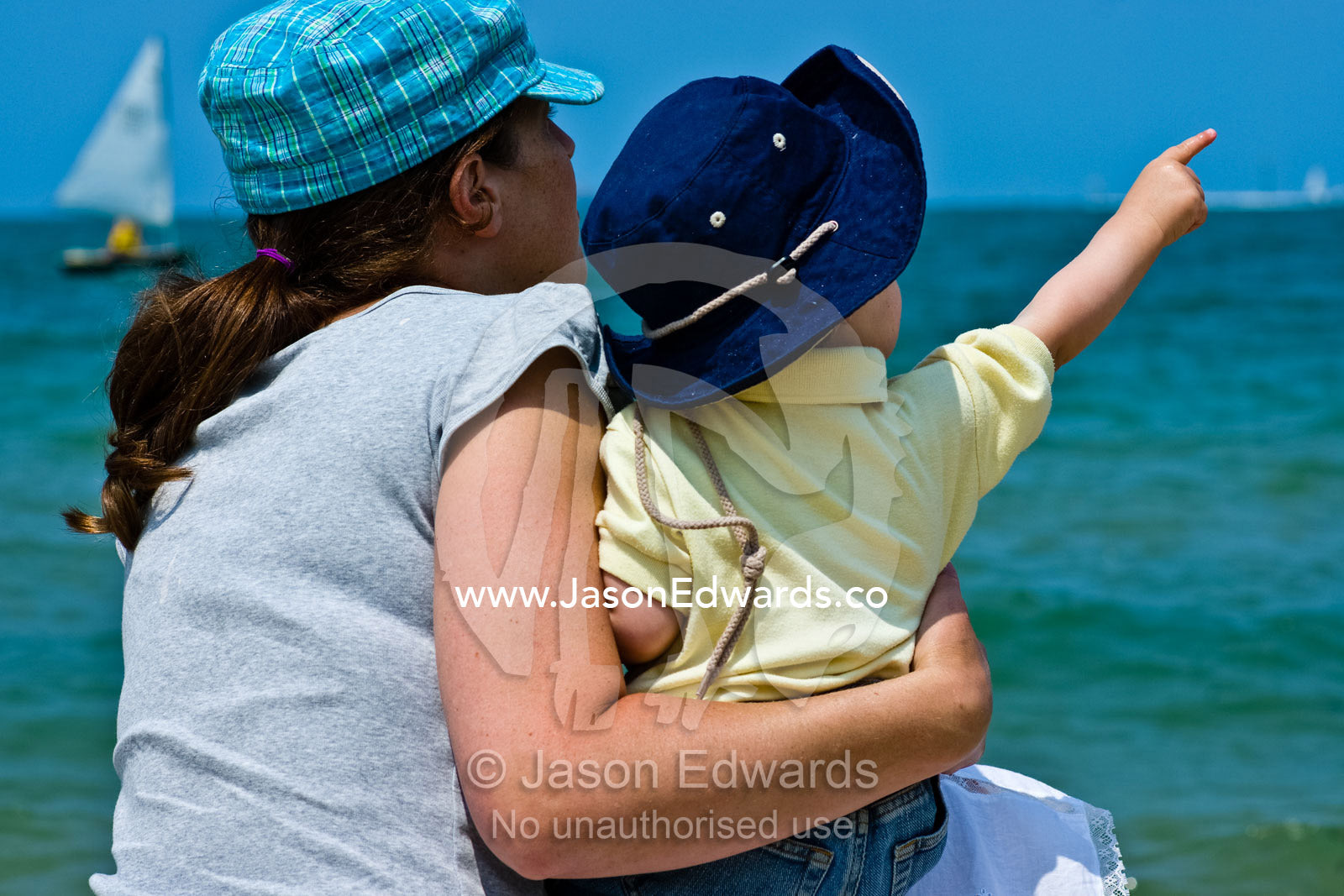 A mother and her son watch sea birds over the ocean on a winters day. Port Melbourne, Victoria, Australia.