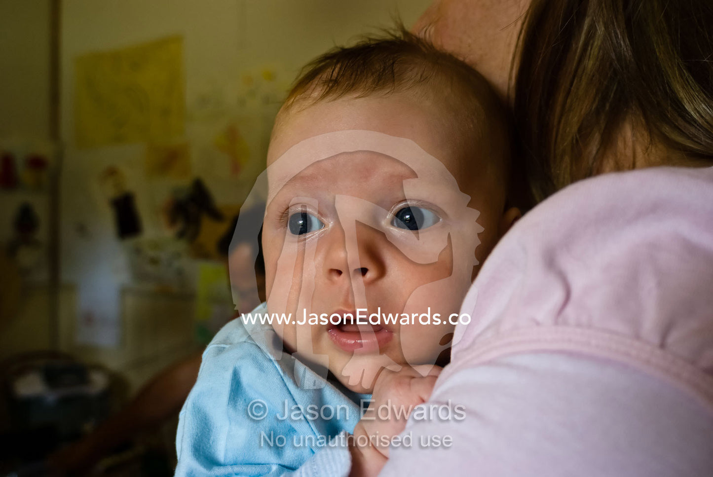 The wide-eyed stare of a new baby cradled on his mothers shoulder. East Malvern, Victoria, Australia.