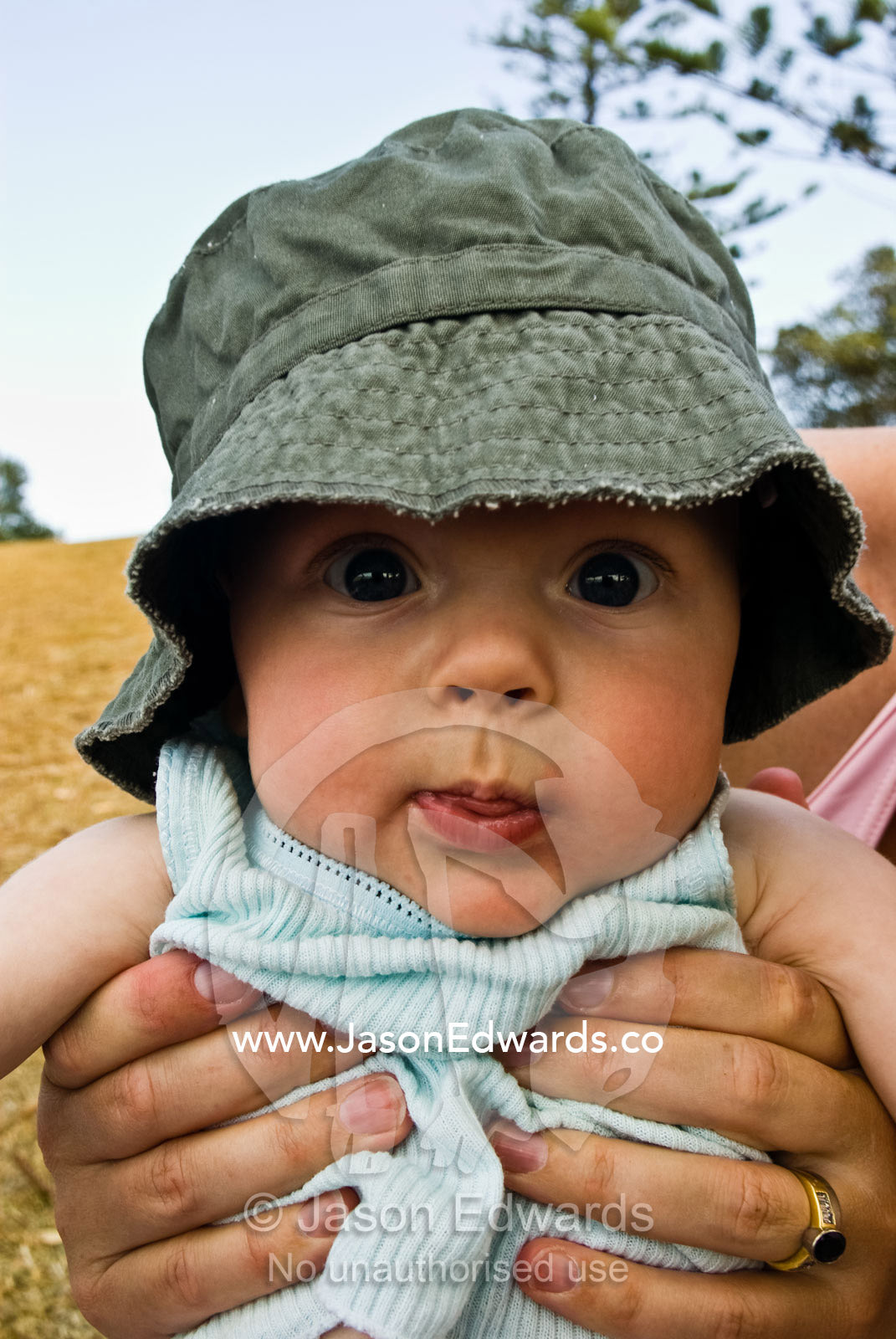 A wide-eyed baby poking out his tongue at the camera. Cosy Corner, Torquay, Victoria, Australia.
