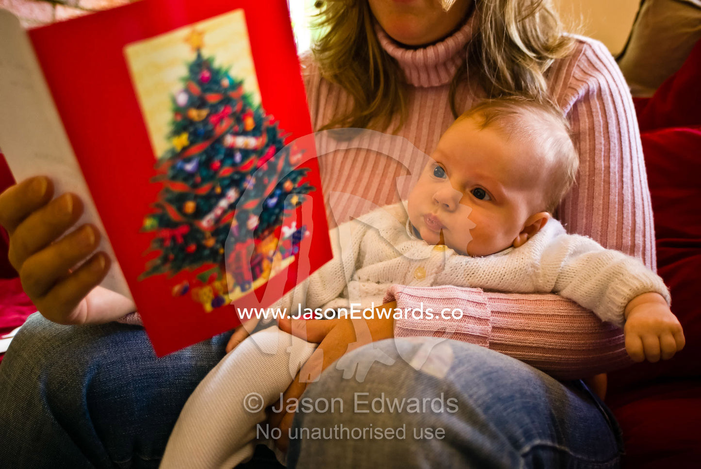 A small baby finds his first Christmas card fascinating reading. North Carlton, Victoria, Australia.