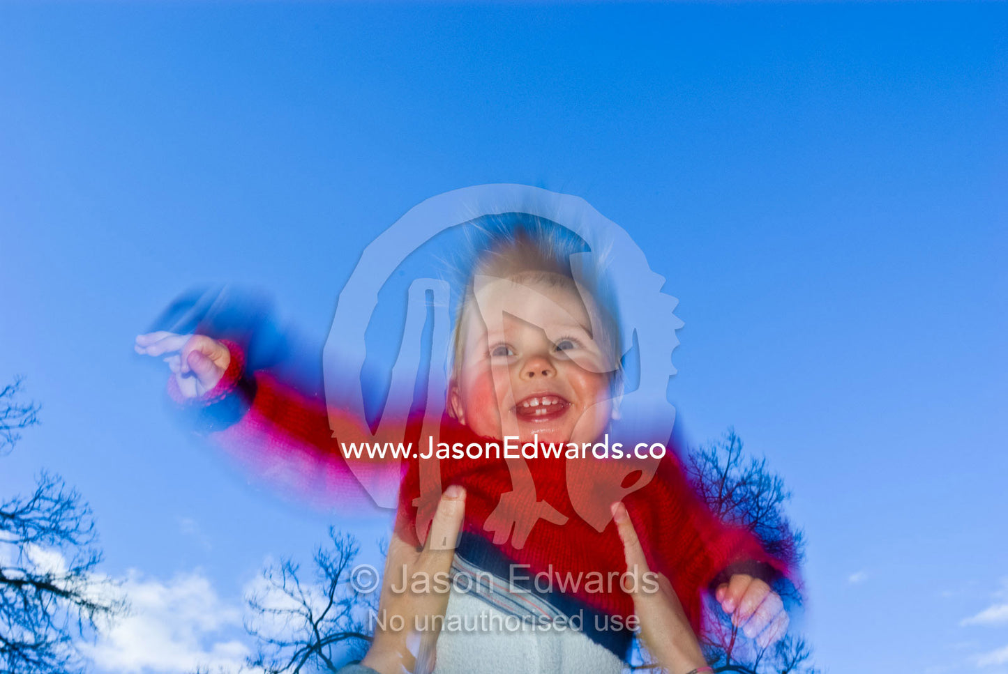 A baby's beaming smile as he flies upward in his mother's arms. Curtain Square, North Carlton, Victoria, Australia.