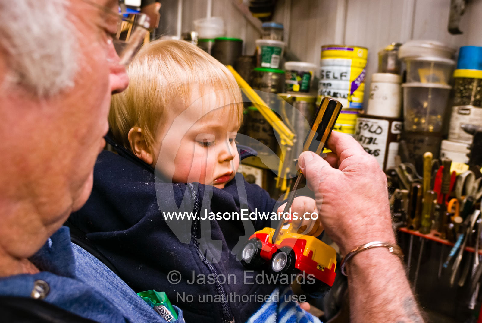 A grandfather and his grandson fix his toy truck with a screwdriver. Jamieson, Victoria, Australia.