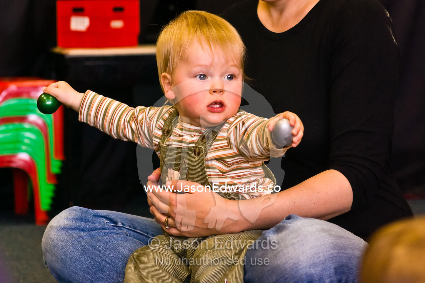 A baby using egg-shaped rattles to make sounds in a music school. Carlton North, Victoria, Australia.