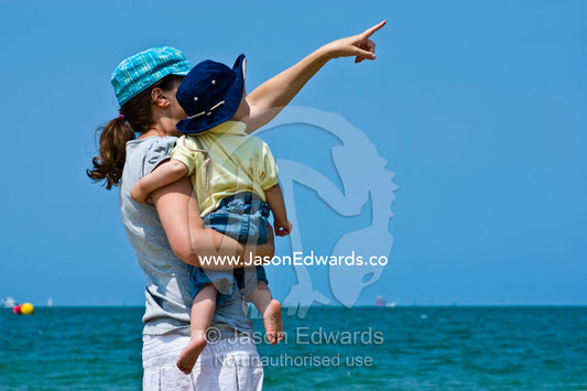A mother and her son watch sea birds over the ocean on a summers day. Port Melbourne, Victoria, Australia.