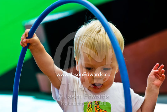 A young boy plays with a large hula hoop in a children's playground. Museum Victoria, Carlton, Victoria, Australia.