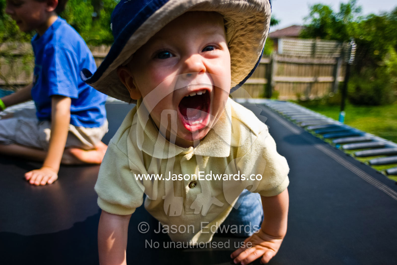 A baby charging along a trampoline whilst playing with his cousin. East Malvern, Victoria, Australia.