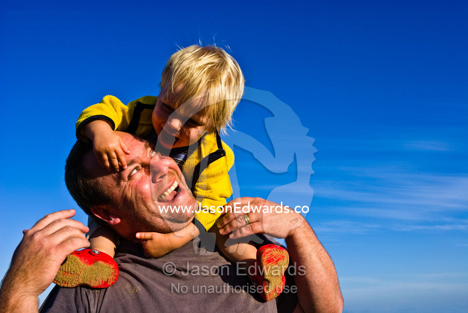 A baby rides on his fathers shoulders during a game of piggyback. Torquay, Surf Coast, Victoria, Australia.