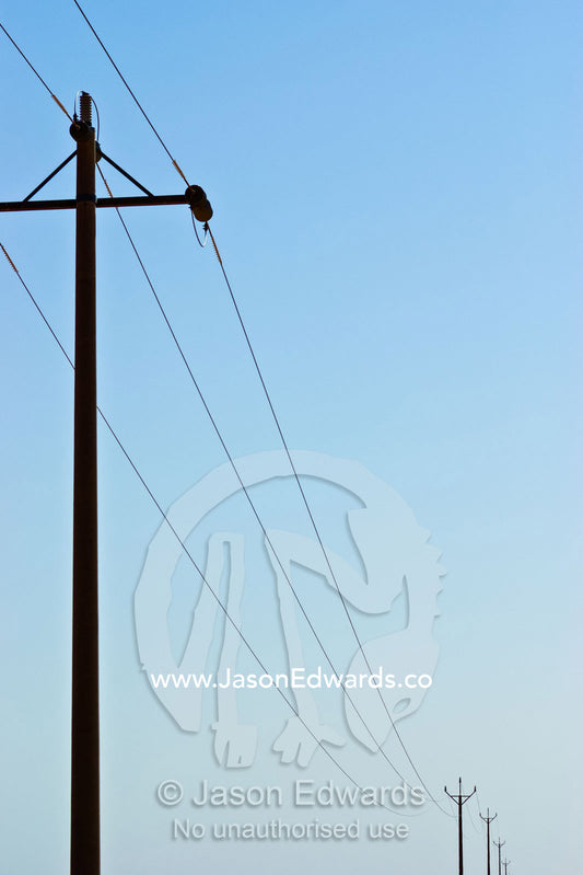 Telegraph poles and cables rise into the clear desert sky. north of Broken Hill, New South Wales, Australia.