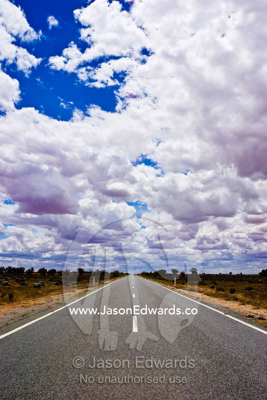Rain storm clouds build over a straight desert highway in the outback. Silver City Highway, between Wentworth and Broken Hill, New South Wales, Australia.